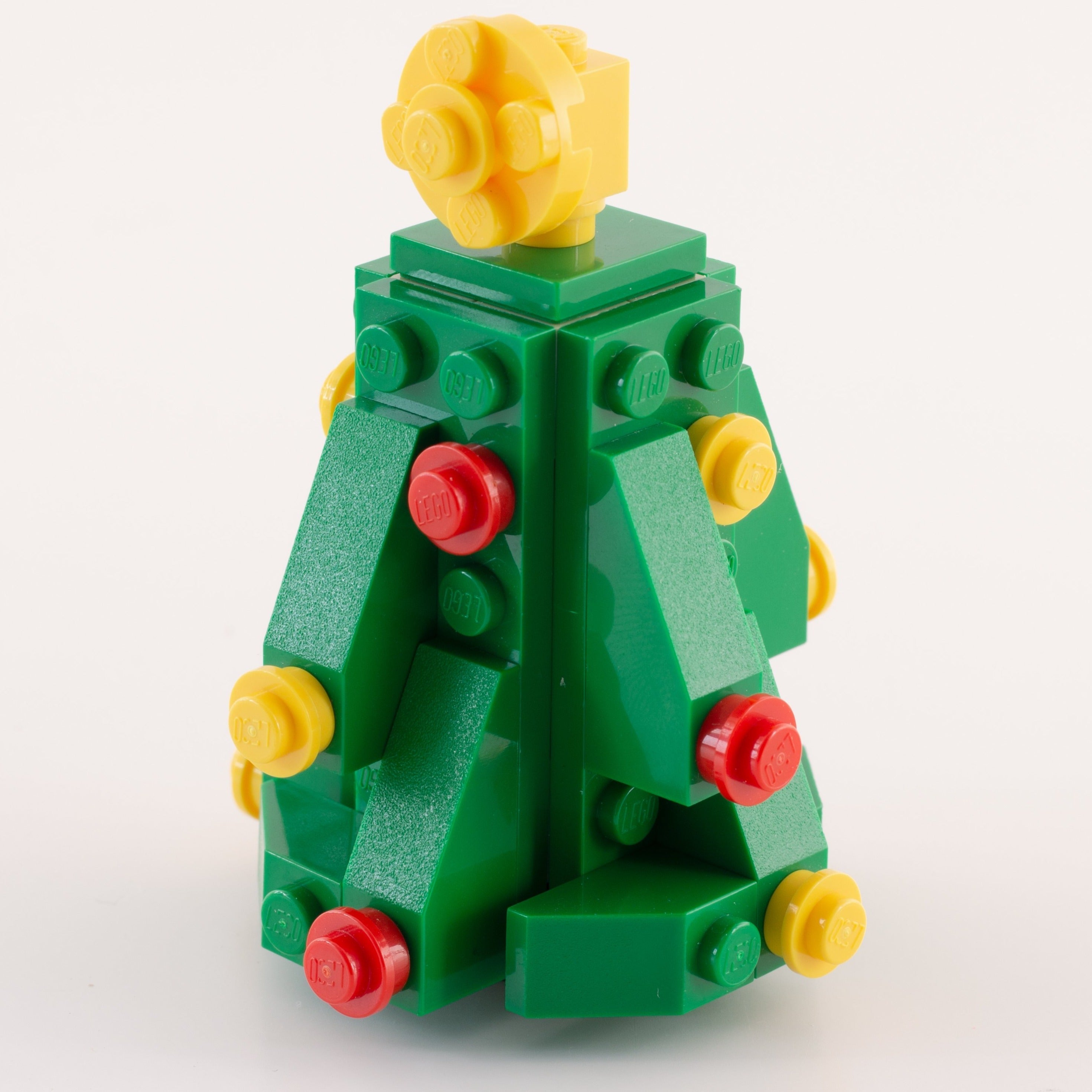 Toy figure made of interlocking bricks with a yellow head and green body on a white background
