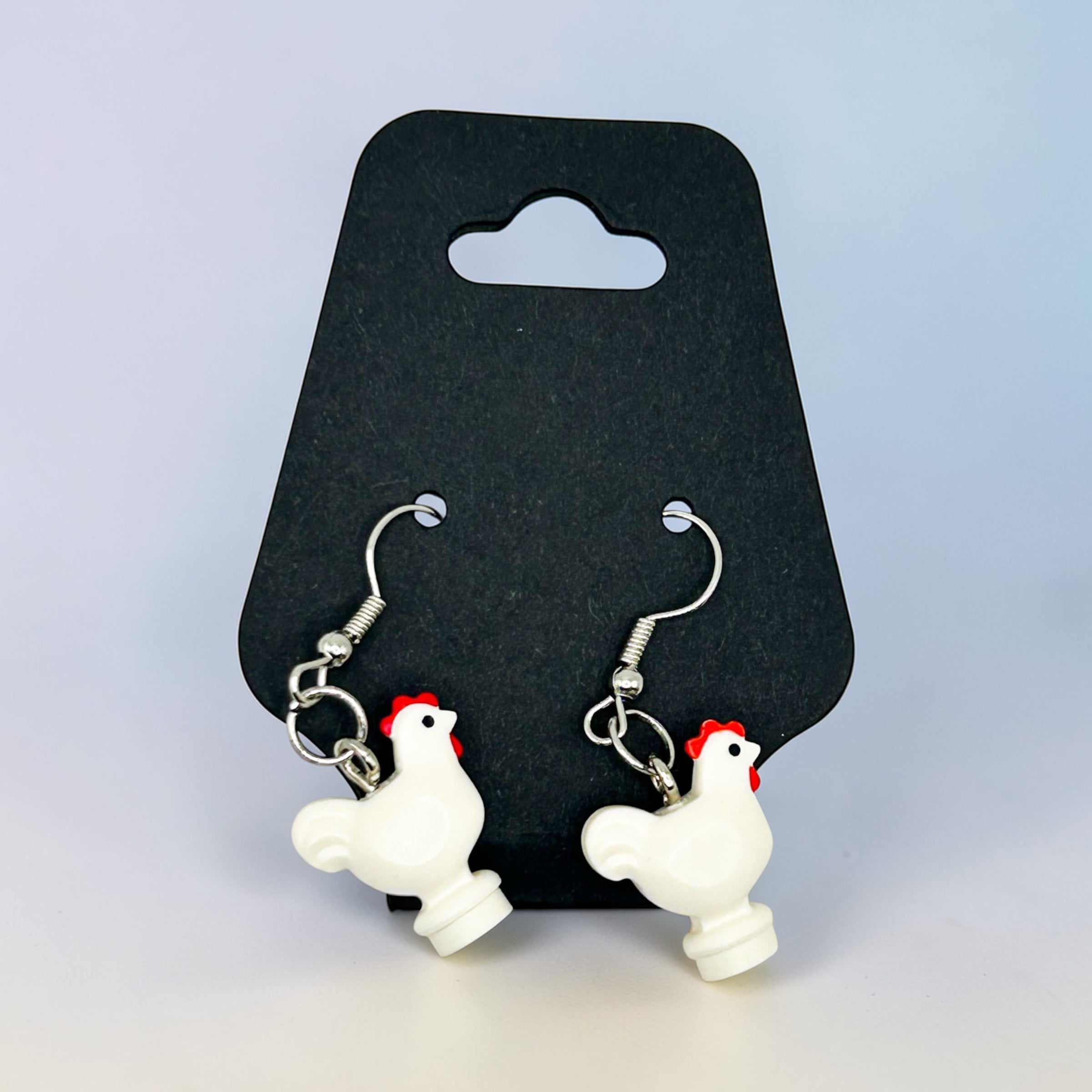 Chicken-shaped earrings on a black card with a light gray background