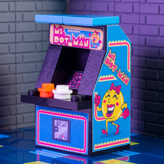 Miniature arcade machine with colorful design against a brick wall background