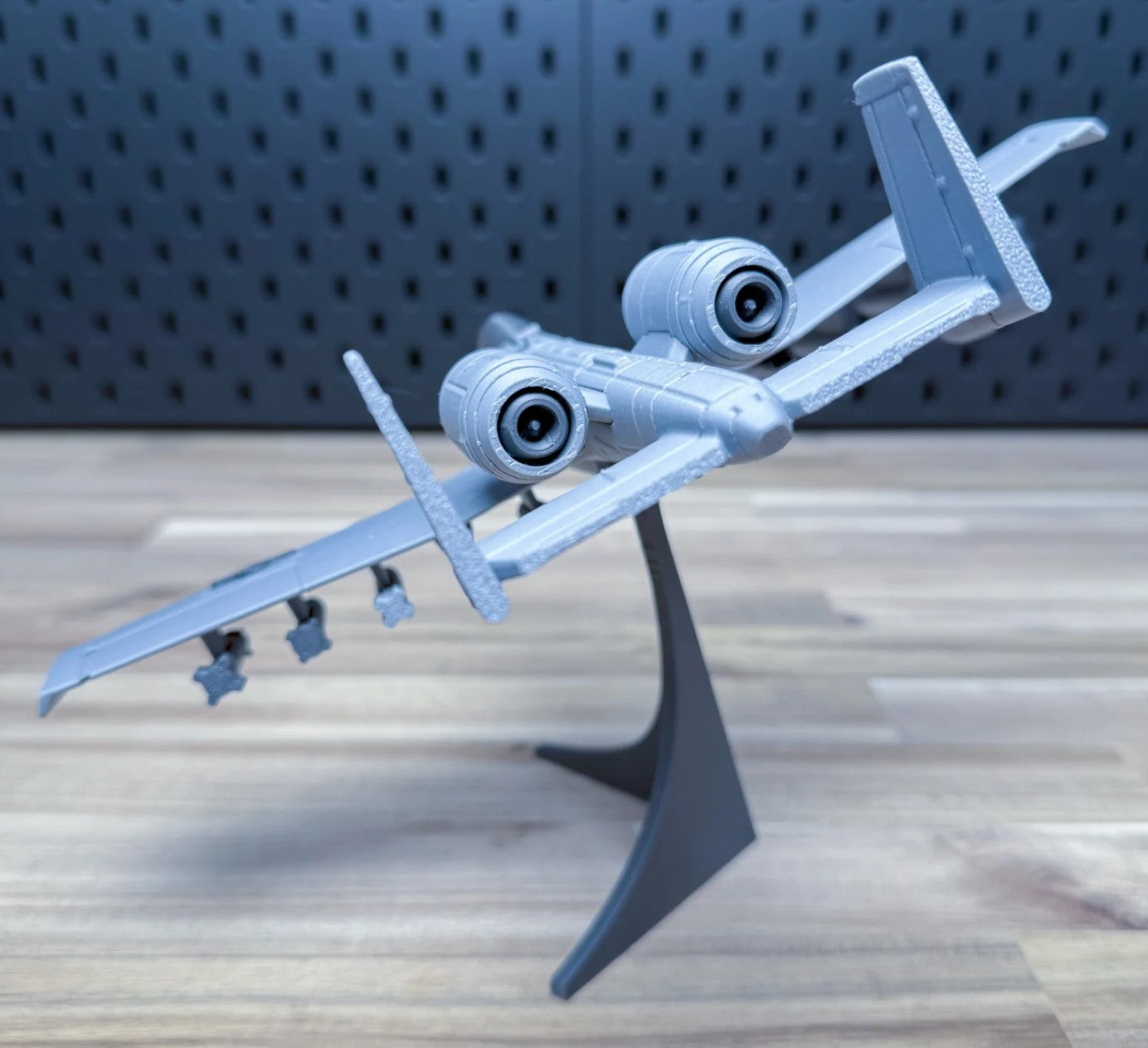 Model airplane on a stand against a perforated metal background
